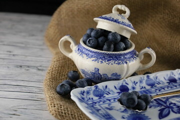 Bowl of fresh blueberries on on a piece of jute, Close up. European blueberry in a blau bowl on jute fabric and wooden table. 