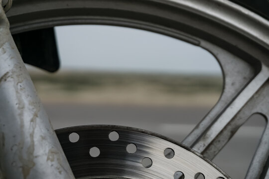 Motorcycle wheel on the background of an asphalt road in the Kazakh steppe, in cloudy weather in the desert