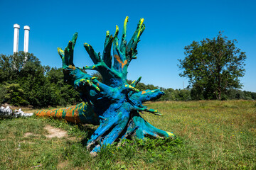 A blue painted tree trunk laying in the lawn nearby the river Isar at Munich, Bavaria, Germany