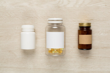 Plastic bottles with vitamins on wooden background, top view
