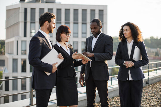 Group of international corporate investors signing contract about cooperation while meeting on company rooftop. African american businessman making electronic signature on digital tablet.