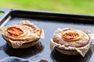 casserole with cheese and tomato. Two servings of round casseroles on a baking sheet.