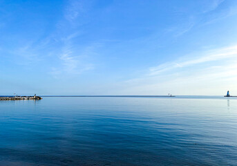 Calm blue waters of northern Lake Michigan with a cove and lighthouse in the disntance