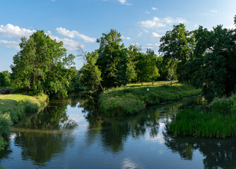 Fototapeta na wymiar krajobraz rzeki Osobłogi w zachodniej Polsce w jasnych zielono niebieskich barwach i lekko pochmurnej pogodzie 
