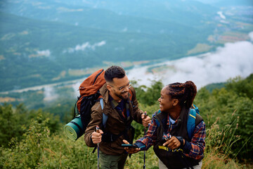Cheerful mixed race couple has fun while hiking in mountains.