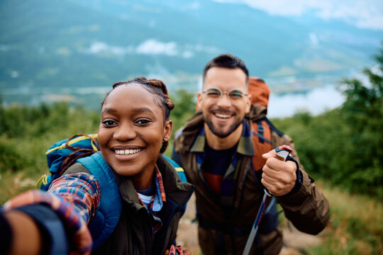 Happy couple of hikers taking selfie on top of hill.