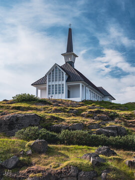 Modern exterior design of Icelandic church at the top of the rocky mountain with blue sky at the background