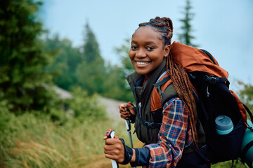 Happy black female hiker on hill looking at camera.