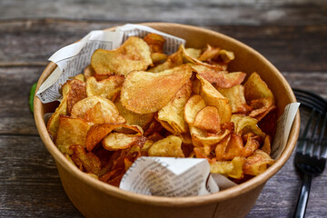 Delicious home made potato chips with sea salt and black pepper against a rustic background. Delicious snack served with sauce. Fast food.Beer snacks