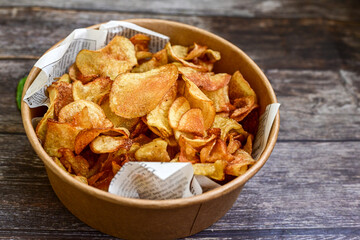 Delicious home made potato chips with sea salt and black pepper against a rustic background. Delicious snack served with sauce. Fast food.Beer snacks