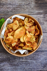 Delicious home made potato chips with sea salt and black pepper against a rustic background. Delicious snack served with sauce. Fast food.Beer snacks