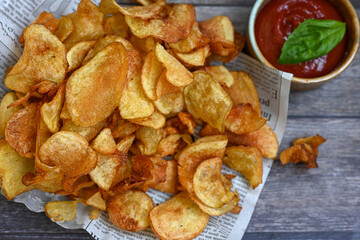 Delicious home made potato chips with sea salt and black pepper against a rustic background. Delicious snack served with sauce. Fast food.Beer snacks