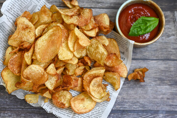 Delicious home made potato chips with sea salt and black pepper against a rustic background. Delicious snack served with sauce. Fast food.Beer snacks