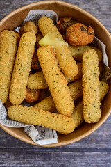 Vegetarian iitalian cheese breaded  oven baked  mozzarella sticks with  fresh basil on wooden background.Italian street food.