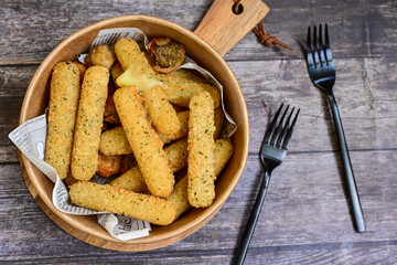Vegetarian iitalian cheese breaded  oven baked  mozzarella sticks with  fresh basil on wooden...