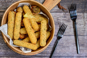 Vegetarian iitalian cheese breaded  oven baked  mozzarella sticks with  fresh basil on wooden background.Italian street food.