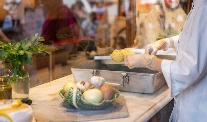 The cook is cooking portuguese traditional dish Pasteis de bacalhau, cod croquettes in a street cafe in Porto