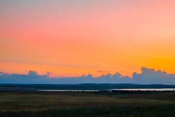 Sky landscape at dawn. Bright sky with clouds over a plain with a lake