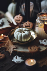 Autumn home composition with aromatic candle, pumpkin, wool sweater, halloween homemade cookies. Aromatherapy on a grey fall morning, atmosphere of cosiness and relax. Holiday handmade decor