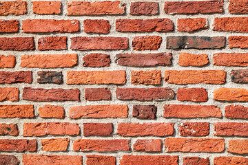 Texture of an old and heavily damaged orange brick wall as an architectural background