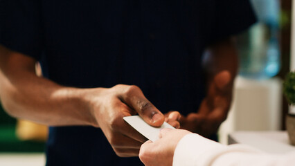 Male tourist receiving room key card for accommodation access after check in at front desk lobby....