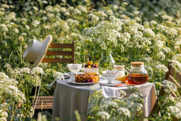 Fancy white porcelain set for herbal tea or coffee and homemade pie on wooden table in the garden....