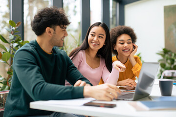 Multiracial students discussing educational project and ideas, studying indoors, sitting in coworking space