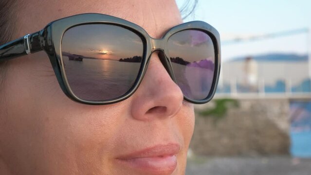 Woman in sunglasses admiring on pier. A smiling pretty woman in sunglasses relax on the beach and feel the sea air in summer.