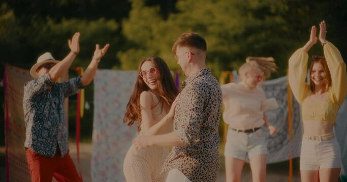 Happy couple dancing bachata while friends cheering at beach