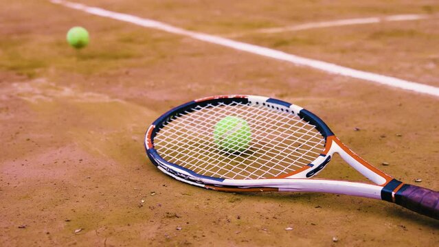 tennis racket with tennis balls lying on a court
