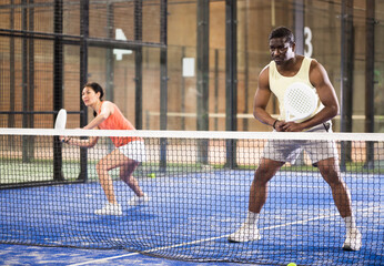 African american man playing paddle tennis indoors