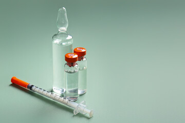 Medical ampules with syringe on green background