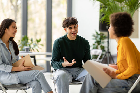 Teamwork concept. International students talking and discussing their educational project together in coworking space