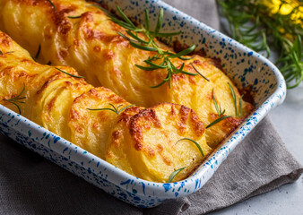 Potato gratin - graten (baked potatoes with cream and cheese) with rosemary and forks (Turkish name; Kremali patates)