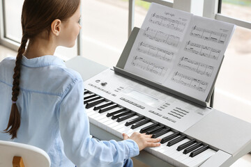 Little girl playing synthesizer at home