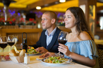 Couple enjoying dinner with wine and having conversation at restaurant