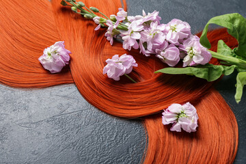 Obraz na płótnie Canvas Ginger hair with beautiful flowers on dark background, closeup