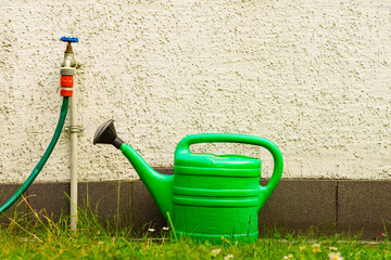 Watering green can on garden plot