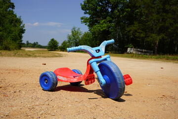 Blue and red used toddler tricycle big wheel bike sitting outside. - obrazy, fototapety, plakaty