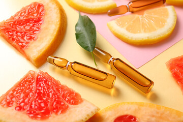 Ampoules with vitamin C and different citrus fruit slices on colorful background