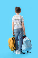 Little schoolboy with backpacks on blue background, back view