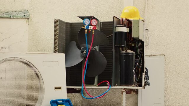 Zoom in shot of damaged external air cooling unit with protection cover removed in need of repairing, with malfunctioning internal parts. Outside condenser not working anymore, ready to be repaired