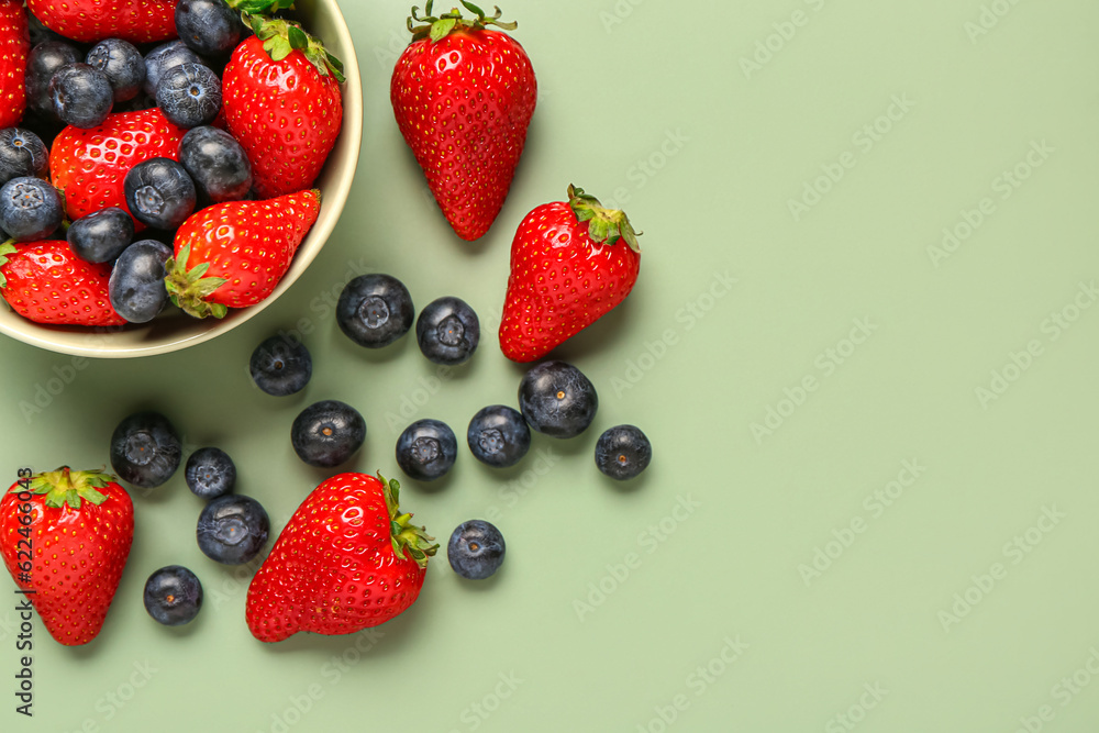 Poster bowl with fresh blueberries and strawberries on green background - Posters
