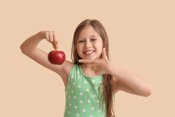 Little girl pointing at apple on beige background