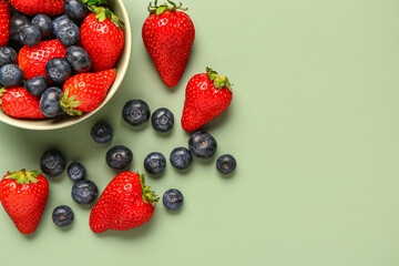 Bowl with fresh blueberries and strawberries on green background © Pixel-Shot