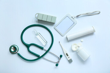 Stethoscope, badge, thermometer, pills and ampule on grey background