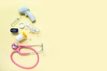Stethoscope, pills, pulse oximeter, infrared thermometer and ampule on yellow background