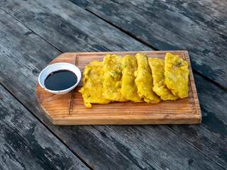 Tempe Goreng Tepung, Tempe Mendoan, flour fried tempeh, tradtional food from Indonesia, on wooden board and vintage table