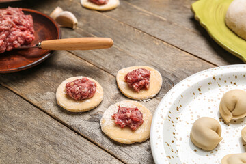 Raw dough with minced meat for preparing dumplings on wooden background