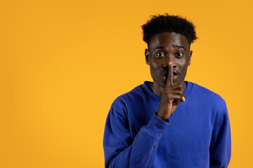 Handsome young black guy showing silence gesture